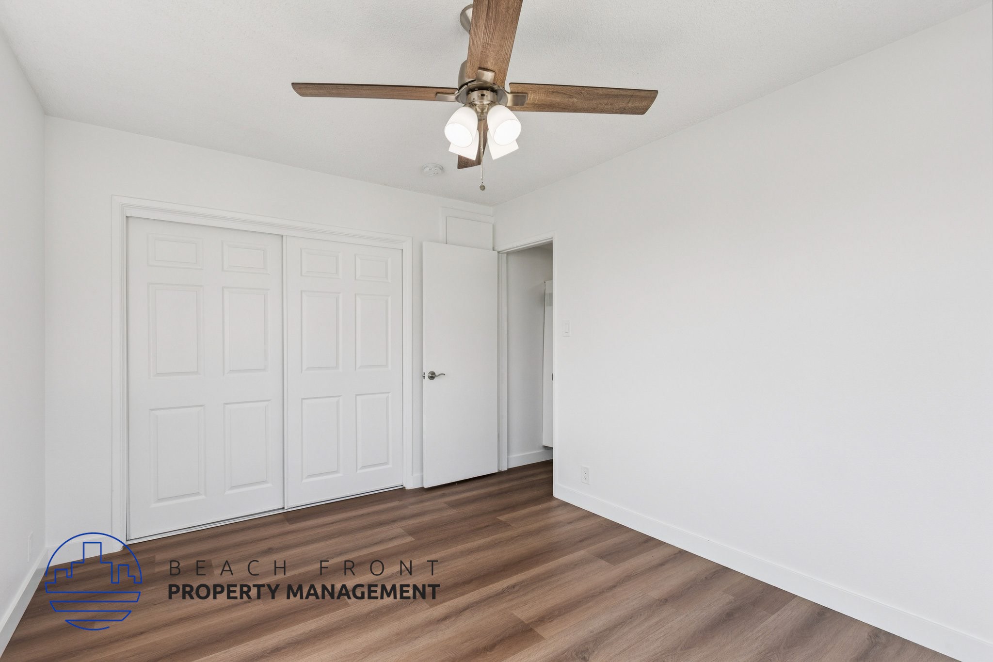 A room with a ceiling fan and two doors.